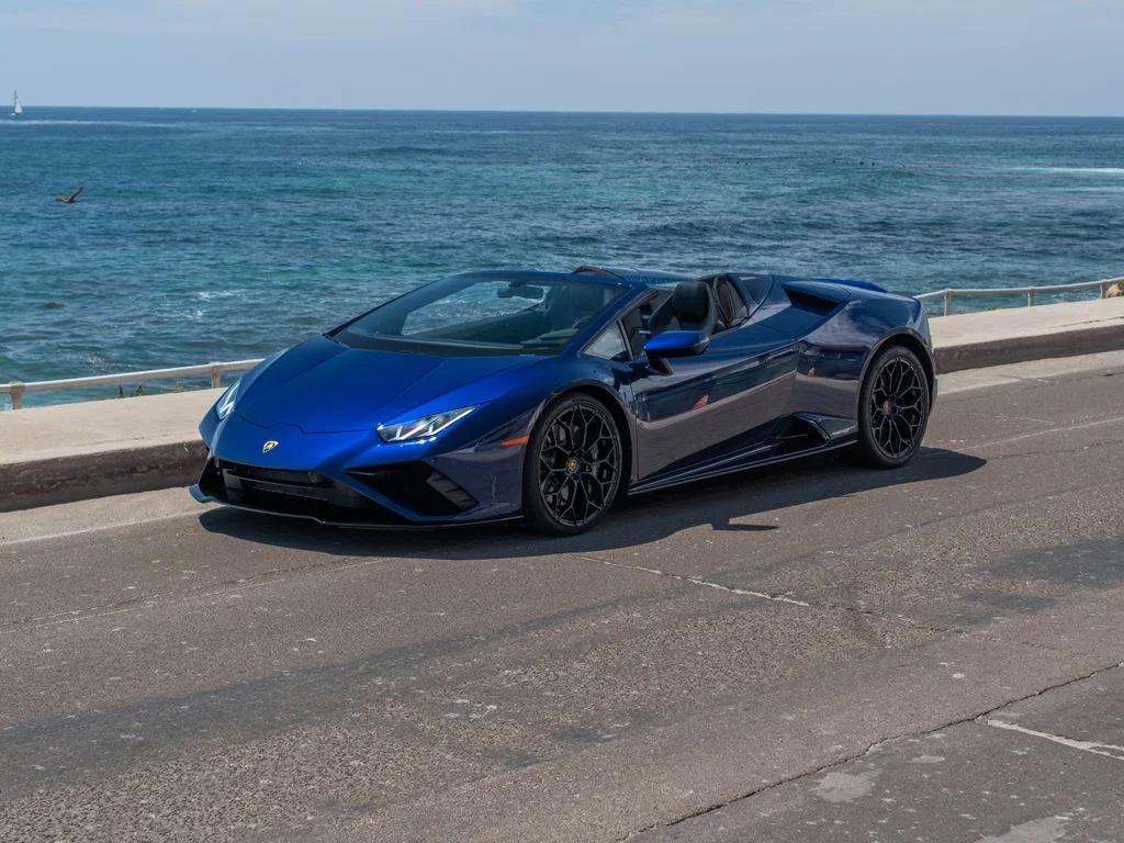 Lamborghini Huracán EVO Spyder bleue, capote ouverte, trois quarts avant en bord de mer
