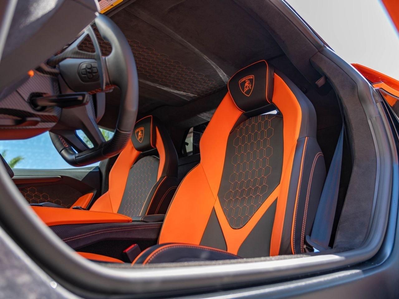 Lamborghini Revuelto, sièges cuir noir et orange, logo Lamborghini sur l'appui-tête