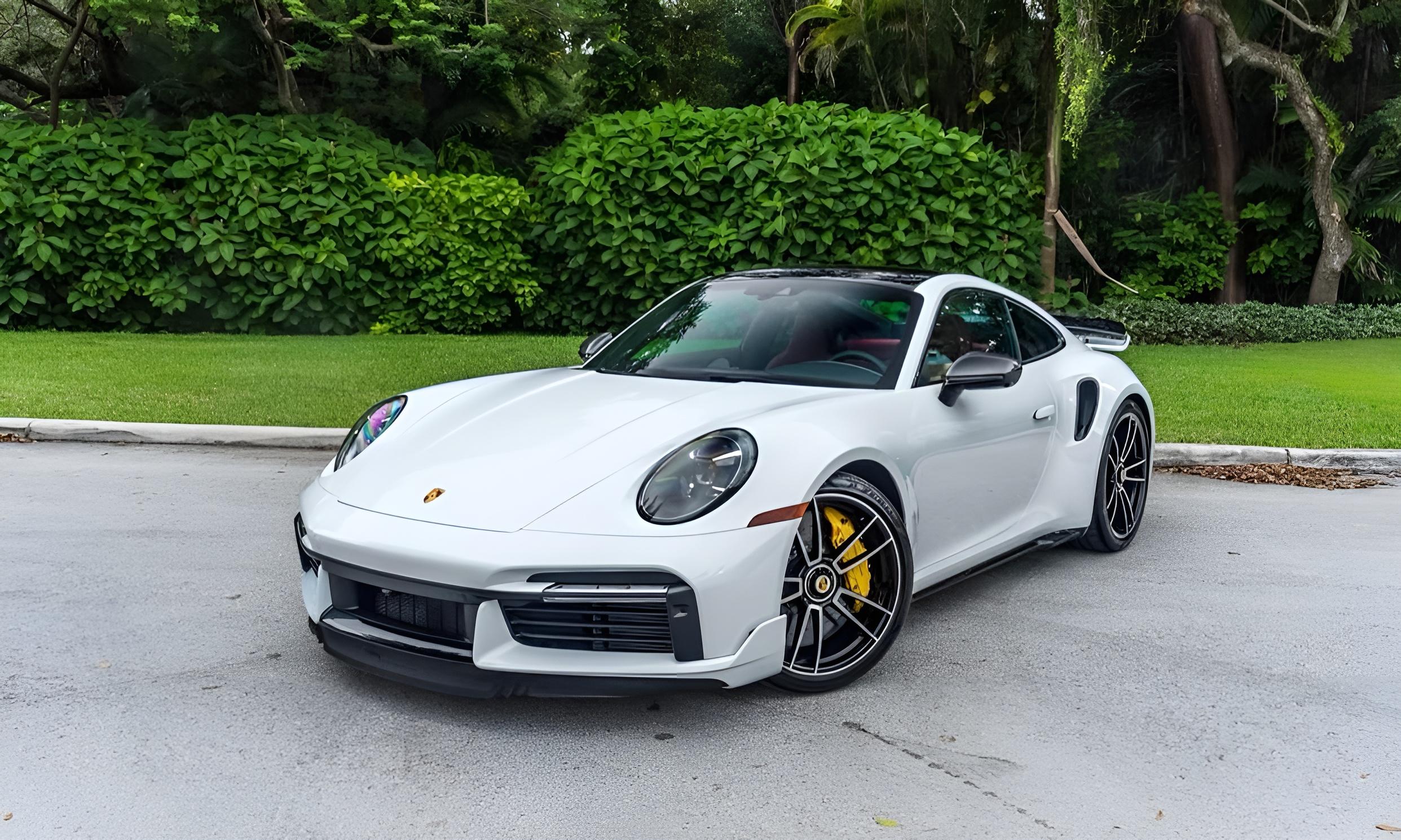 Porsche 911 Turbo S (992) blanche, trois quarts avant, jantes noires et étriers jaunes